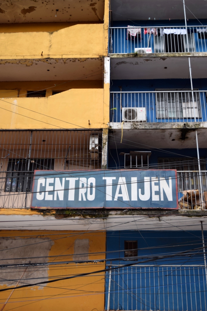 a building facade in ciudad del elste, paraguay, half yellow and half blue, with most of the apartments caged on the balconies