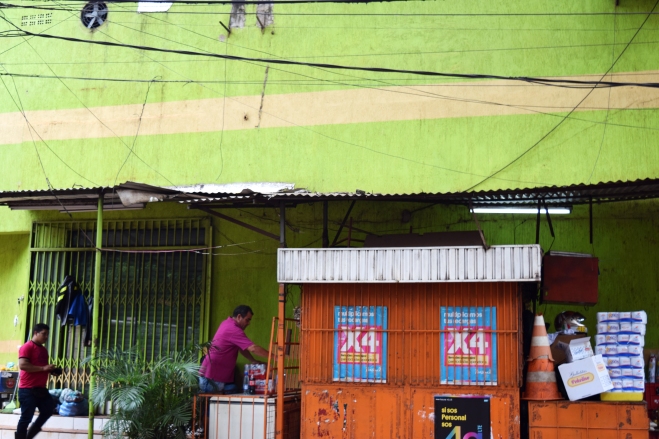 a hawker's stand in front of a citrus green wall in ciudad del este, paraguay